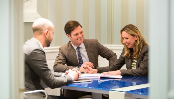 Business people smiling with a client around a table