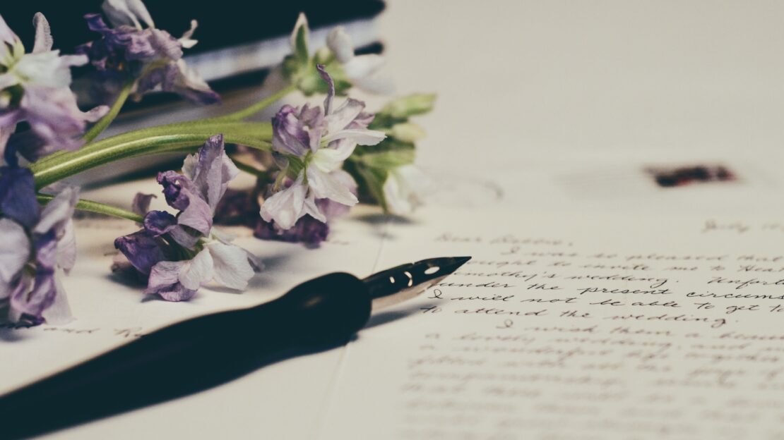 A fountain pen, a page of written words and a bunch of flowers