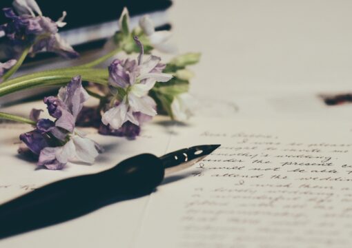 A fountain pen, a page of written words and a bunch of flowers