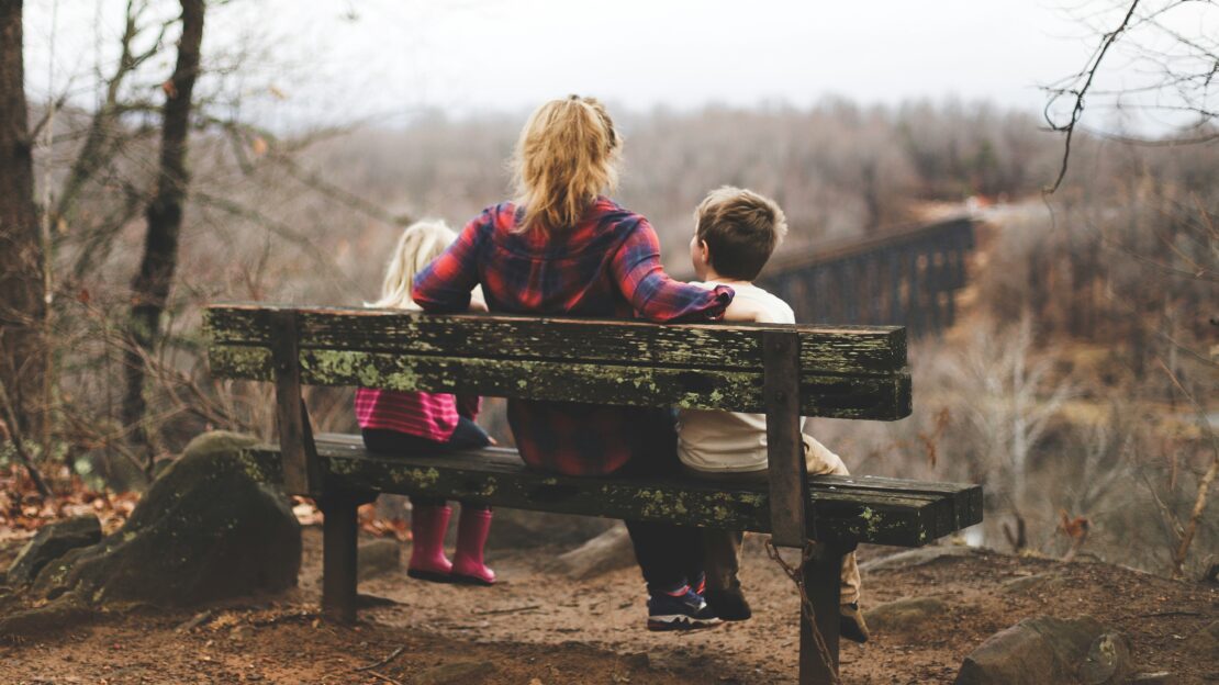 Children sat on a bench with their mother